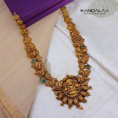 This luxurious 22KT Nakas long necklace features a stunning Lakshmi pendant, accented with vibrant red and green stones. A symbol of prosperity and grace, it adds a royal touch to any occasion. Kandalaa Jewellery, Lakshmi Pendant, Green Stones, A Symbol, Gold Necklaces, Green Stone, Vibrant Red, Long Necklace, Wedding Jewelry