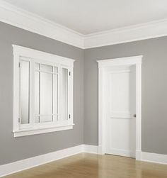 an empty room with gray walls and white trim on the doors, windows and wood flooring