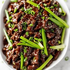 a white bowl filled with meat and green onions