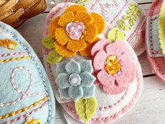 three felt easter eggs decorated with flowers and pearls, sitting on a white wooden surface