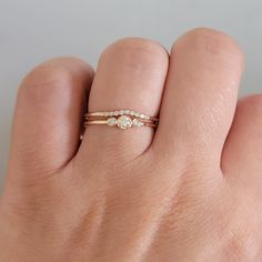 a woman's hand wearing a gold ring with three stones on the middle and one stone in the middle