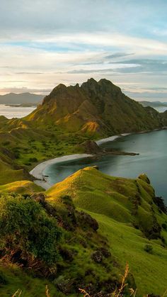 an island in the middle of a lake surrounded by green hills and grass on both sides