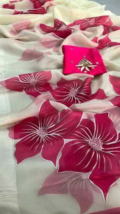 a pink and white flowered table cloth on top of a bed