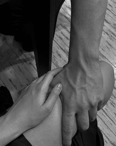 two people holding each other's hands while sitting on the floor in front of a table