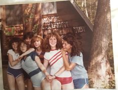 a group of young women standing next to each other in front of a tree house