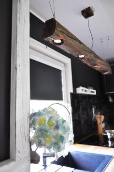 a kitchen with a sink, window and wooden beam hanging from the ceiling above it