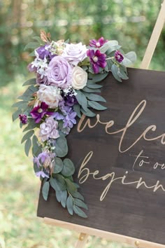 a welcome sign with flowers and greenery on it