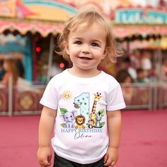 Celebrate your little one's milestone in style with our adorable Personalized Safari First Birthday T-Shirt! Made with love, this custom-printed tee features a charming assembly of jungle animals, including a brave lion and a tall giraffe, all surrounding a vibrant rainbow print. Customize It For Your Little One: When ordering, please provide us with your child's name to make this birthday shirt a truly one-of-a-kind garment. The name will be artistically integrated into the design, just like the smiles on our friendly animals! Quality That Cares: Each shirt is carefully printed onto pure cotton fabric, ensuring a soft touch against your baby's skin, perfect for all-day wear during their birthday bash and beyond. Perfect Fit Promise: To ensure the perfect fit for your little adventurer, we Safari First Birthday, Baby Birthday Shirts, Friendly Animals, Kids Graphic Tees, Rainbow Print, Jungle Animals, Special Birthday, Baby Skin, Animal Party