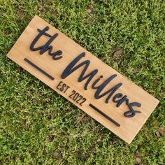 a wooden sign that says the millers on it in black lettering, laying on some green grass