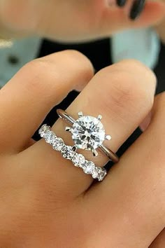 a woman's hand with two rings on her fingers and the ring has an oval diamond