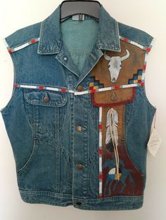 Custom Designed & Crafted Native American Painted & Decorated Blue Denim Art Vest, Sz 3, Small. Vest made by 2022 Denim Co, New with Tags. Wisconsin textile artist Susan Lathrum Creation. Hand or machine wash gentle. Front metal button closure. Left front motif has one hanging white leather fringe. Back motif has feather & bison motif with five white leather hanging fringes. There are two front chest pockets and two front slash pockets. Back waist has adjustable side buttons. Use mea Upcycle Jean Jacket, Native American Style Outfits, Denim Jacket Diy Paint, Diy Denim Jacket, Denim Crafts Diy, Native American Patterns, Denim Art, Diy Jacket, Denim Ideas