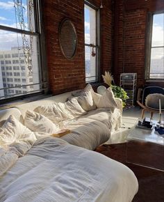 a living room filled with lots of furniture next to large windows on top of a building