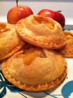 some apple pies are on a plate with apples in the backgroung