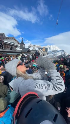 a crowd of people standing next to each other in front of snow covered mountains and buildings