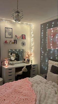 a bedroom decorated in pink and grey with lights on the wall, vanity desk and bed