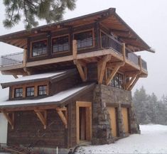 a large wooden building sitting on top of a snow covered slope next to a forest