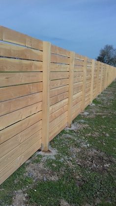 a wooden fence is shown with grass and dirt on the ground in front of it