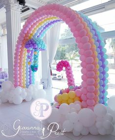 an arch made out of balloons in the shape of a number one and rainbow colors