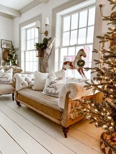 a living room filled with lots of furniture and a christmas tree in front of the window