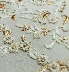 an embroidered fabric with gold and white flowers on it