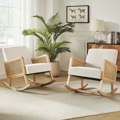 two white rocking chairs sitting on top of a wooden floor next to a potted plant