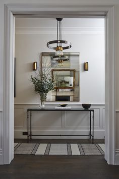 an entry way with a table, mirror and vase