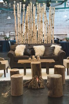 a living room filled with lots of furniture and wooden sticks hanging from the ceiling above