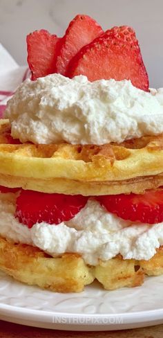 a stack of waffles topped with whipped cream and strawberries