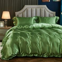 a green comforter with ruffled edges on a bed in a blue room next to a lamp