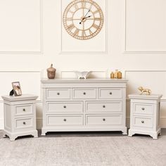 two white dressers sitting next to each other in front of a wall with a clock on it