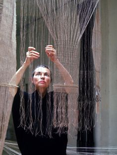 a woman standing in front of a curtain with her hands on the top of it