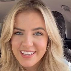 a woman sitting in the back seat of a car looking at the camera and smiling