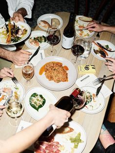 people sitting around a table eating food and drinking wine