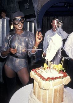 a woman holding a knife in front of a cake on a table with other people