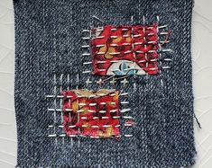 a close up of a piece of cloth with pins and needles in the shape of squares