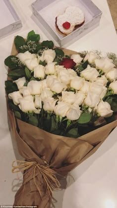 a bouquet of white roses sitting on top of a table