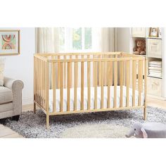 a baby's crib in the corner of a room with a couch and chair