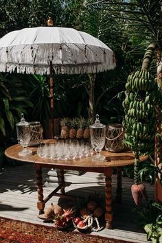 a table with glasses and an umbrella on it in the middle of a garden area