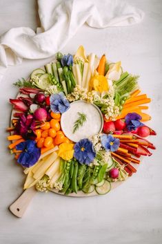 a platter filled with vegetables and dip surrounded by white napkins on the side