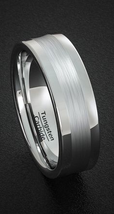 a wedding band that has been made with white gold and silver in the center, on a black surface