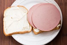 a sandwich with two slices of bread and cream cheese on it sitting on a white plate