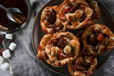 several pecan pies on a plate next to some marshmallows and syrup