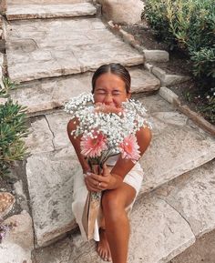 a woman sitting on steps with flowers in her hand