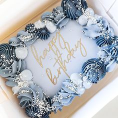 a blue and white cake in a box with congratulations written on the side, surrounded by frosting