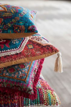 multicolored pillows stacked on top of each other with tassels hanging from them