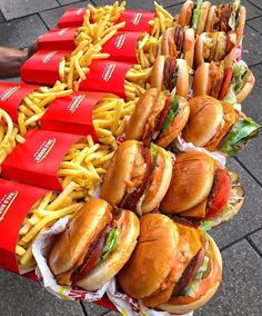 a table topped with lots of sandwiches and fries next to red bins filled with french fries