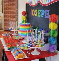 a table filled with lots of colorful desserts next to a chalkboard that says joseph