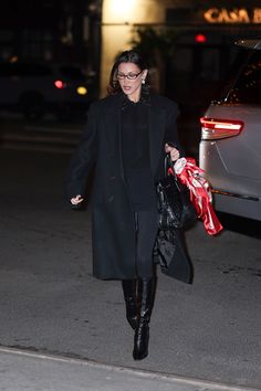 a woman walking down the street carrying shopping bags in her hand and wearing black boots