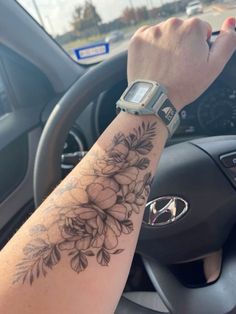 a woman's arm with flowers on it and a wrist watch in the car