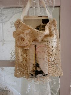 a bag hanging from the side of a window next to a lace covered door frame with an eiffel tower on it